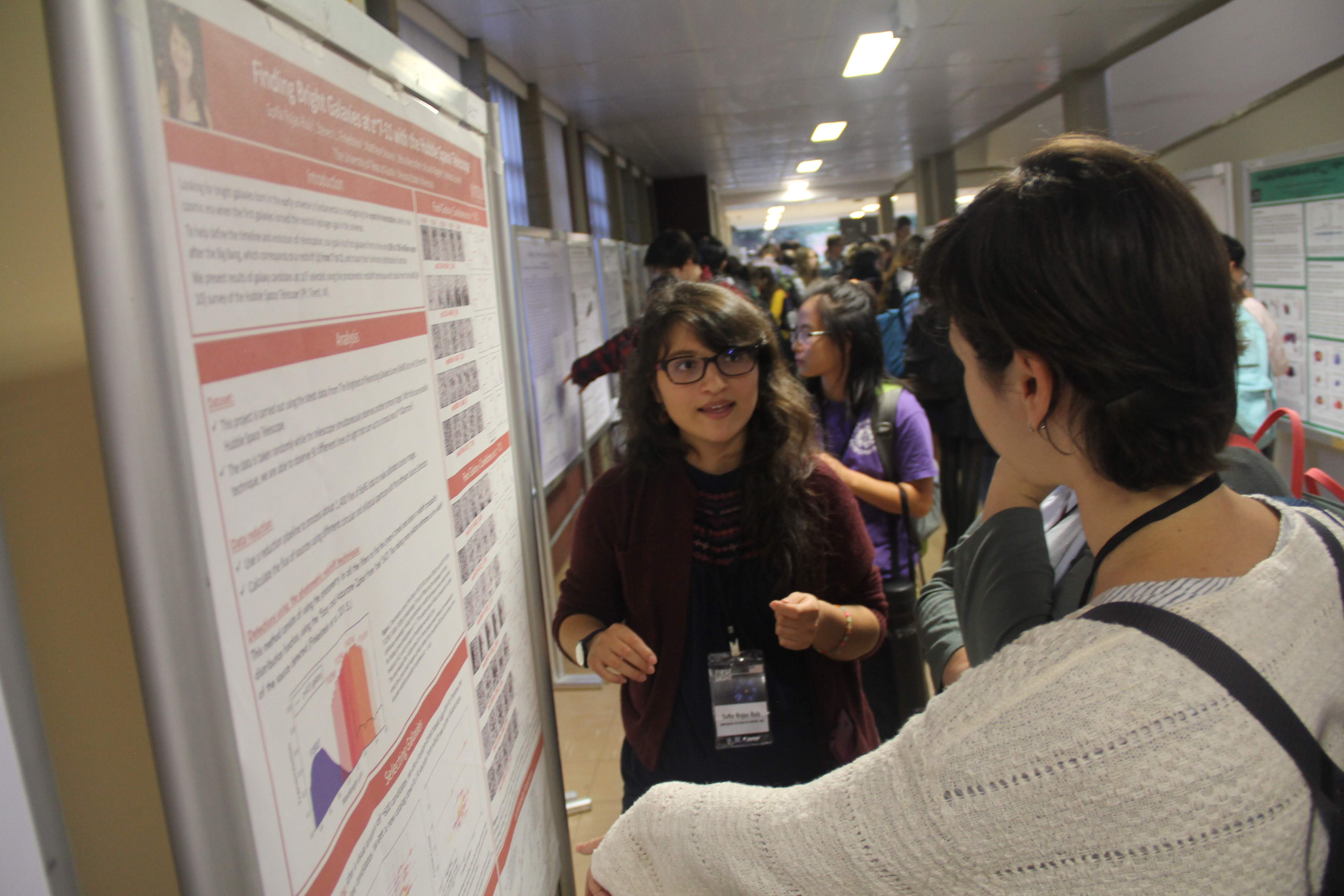 Photo of Sofía Rojas presenting a poster of her research at the First Light School in Sao Paulo, 2019.